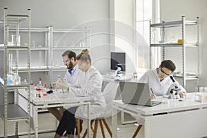 Group of busy medical scientists working in modern pharma or biotech science laboratory