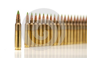 A group of 5.56 calibar, green tip bullets ordered into the line on white background photo