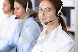 Group of callcenter operators at work. Focus at beautiful business woman in headset