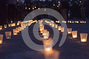 A group of candles burning in street and people holding candles in the background. Day of Memory of the Bereaved