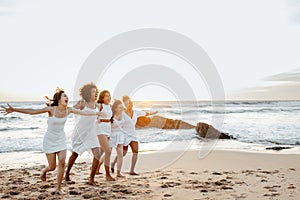 Group of carefree women running at the beach, having fun and enjoying hen party celebration on coastline