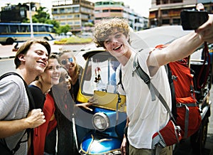 A group of Caucasian tourists taking selfie in front of a Tuk Tu