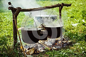 A group of cauldrons and kettle are hanged upon fire