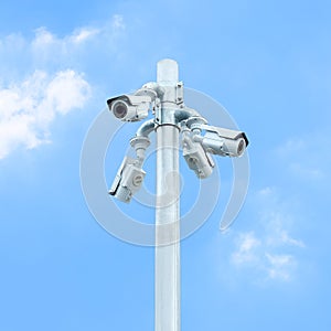 Group of CCTV on post with cloudy blue sky