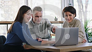 Group of charismatic and smiling large friends two ladies one guy meeting at the coffee shop they using laptop to watch
