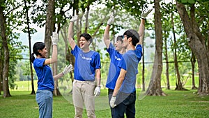 A group of cheerful Asian volunteers raised hands to celebrate their successful charity event