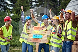 A group of cheerful both female and male builders posing for a photo at a cottage construction site. Construction, building,