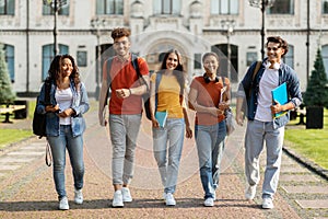 Group of cheerful college students walking out of campus together