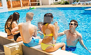 Group of cheerful couples drinking cocktailsin the pool