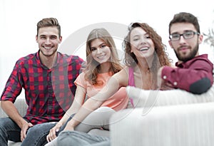 Group of cheerful friends sitting on sofa