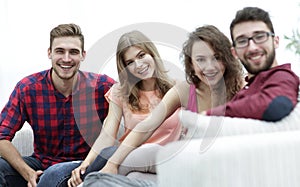 Group of cheerful friends sitting on sofa