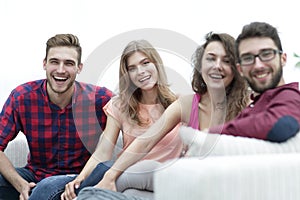 Group of cheerful friends sitting on sofa