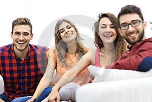 Group of cheerful friends sitting on sofa