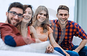 Group of cheerful friends sitting on sofa