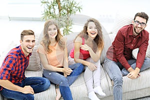 Group of cheerful friends watching videos, sitting on the couch