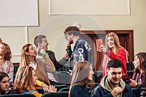 The group of cheerful happy students sitting in a lecture hall before lesson