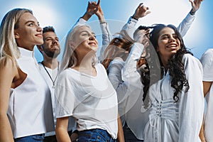 Group of cheerful joyful young people standing and celebrating together over blue background