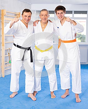 Group of cheerful martial arts fighters of different ages in training room