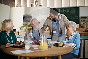 Group of cheerful seniors enjoying breakfast in nursing home care center.