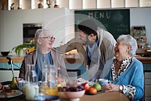 Group of cheerful seniors enjoying breakfast in nursing home care center.