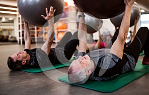 A group of cheerful seniors in gym doing exercise with fit balls.