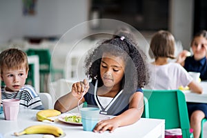 A group of cheerful small school kids in canteen, eating lunch.