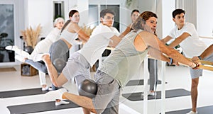 Group of cheerful sports people of different ages practicing pilates with a ball in the gym of a modern fitness studio.