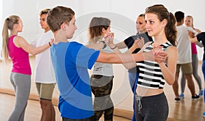 Group of cheerful teen dancing tango in dance studio