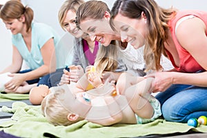 Group of cheerful women learning to take care of their babies