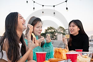 Group of cheerful young Asian female friends are enjoying partying on a rooftop restaurant together