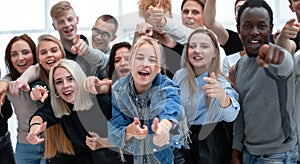 Group of cheerful young people pointing at you