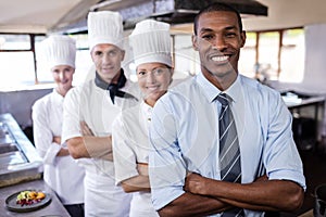 Group of chefs and manager standing with arms crossed in kitchen