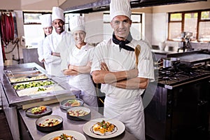 Group of chefs standing with arms crossed in kitchen photo