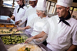 Group of chefs stirring prepard foods in kitchen