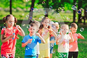 Group of children blowing soap bubbles in a garden