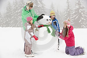 Group Of Children Building Snowman On Ski Holiday