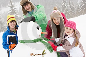 Group Of Children Building Snowman On Ski Holiday