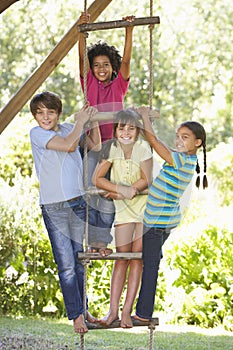 Group Of Children Climbing Rope Ladder To Treehouse