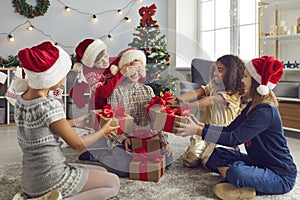 Group of children covering their friend`s eyes before giving their Xmas presents and surprises