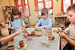 Group of children decorating their clay pottery