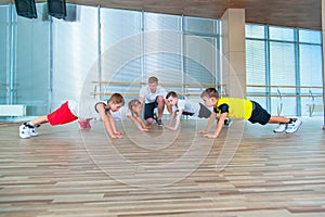 Group of children doing kids gymnastics in gym with teacher. Happy sporty children in gym. bar exercise. plank.