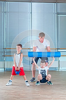 Group of children doing kids gymnastics in gym with teacher. Happy sporty children in gym. foam roller