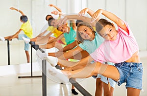 Group of children doing leg stretch at ballet barre