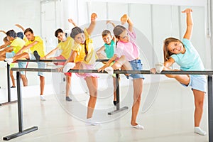 Group of children doing leg stretch at ballet barre