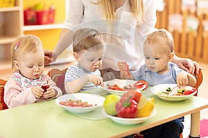 Group of children eating from plates in day care centre