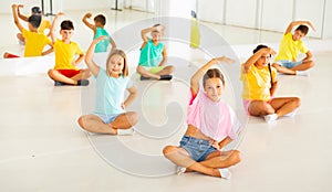 Group of children exercising during yoga class in fitness center - vakrasana pose photo