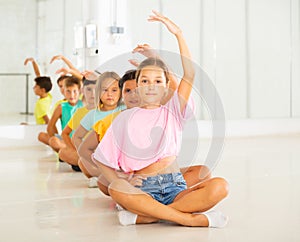 Group of children exercising during yoga class in fitness center - vakrasana pose photo