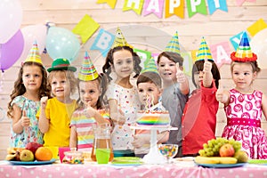 Group of children having fun celebrating birthday party. Kids showing thumbs up sign