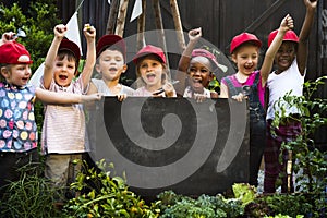 Group of children holding blank blackboard in garden