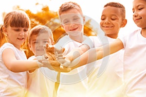 Group of children joining hands in park on sunny day